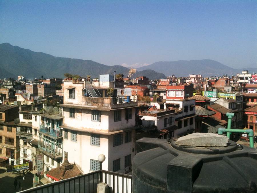 Brick rooftops of Kathmandu with hills behind